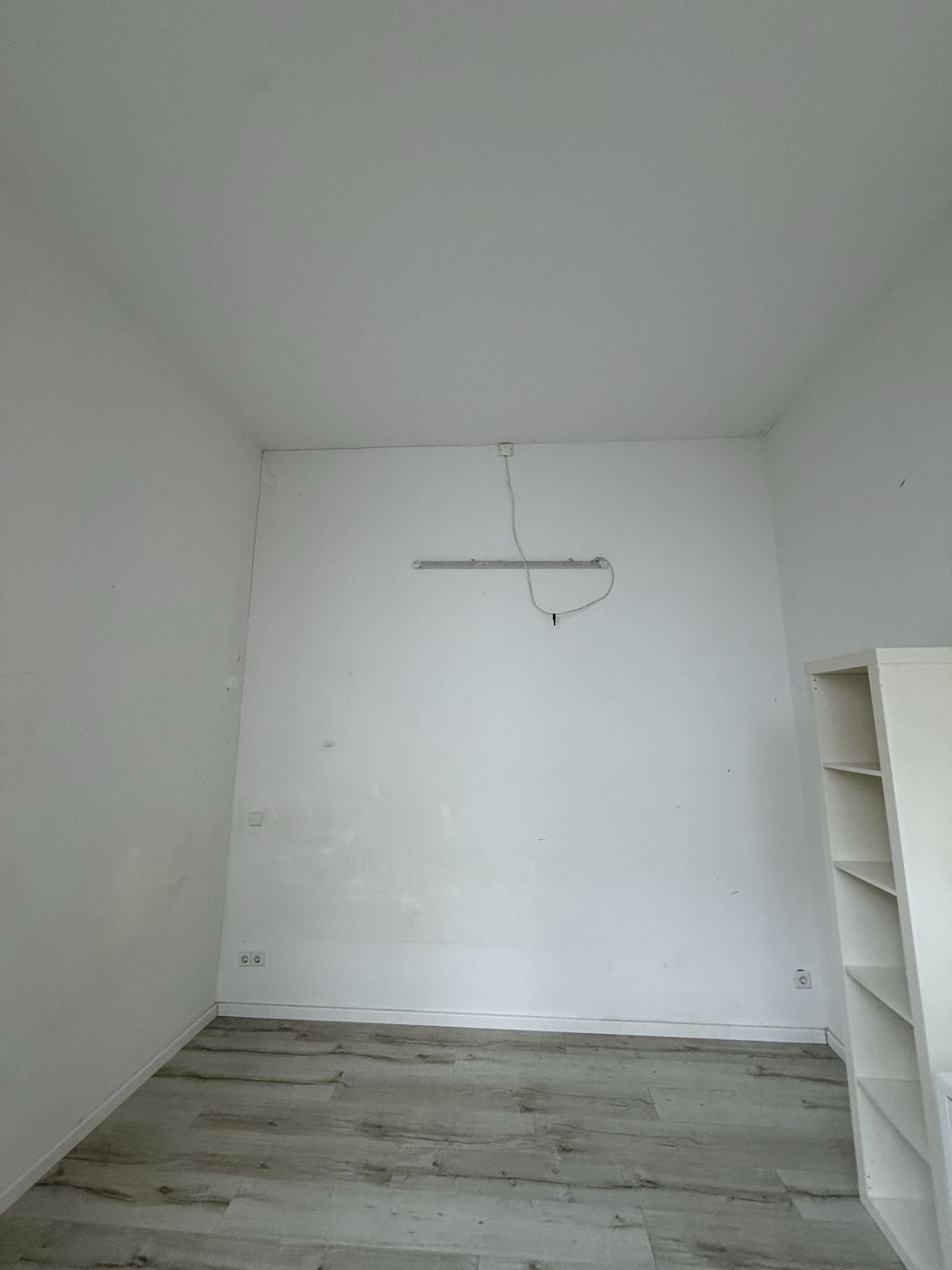 Zimmer vor der Instandsetzung mit Leuchtschiene und Flecken an der Wand
